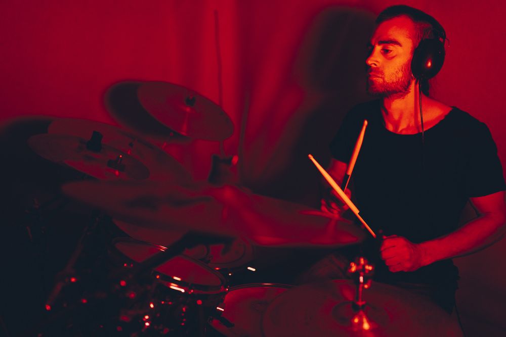Man with drumsticks playing on drums in redness