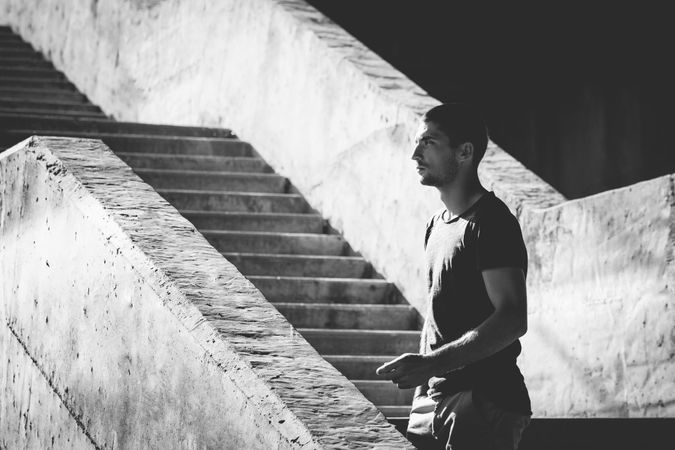 B&W shot of man standing on outdoor cement staircase