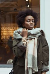 Woman wearing green jacket and gray scarf standing outdoor