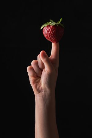 Kid balancing strawberry on finger