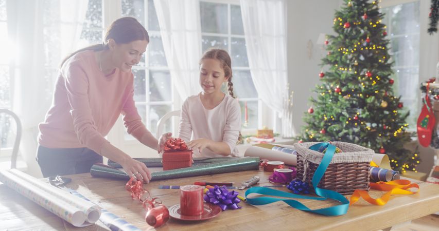 Portrait of Mother and Daughter Wrapping Gifts for Christmas at Home.