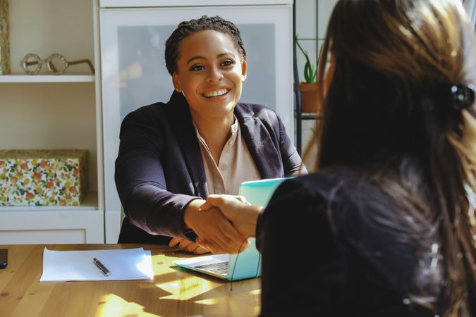 Confident business owner shaking hands after a meeting with colleague in bright office