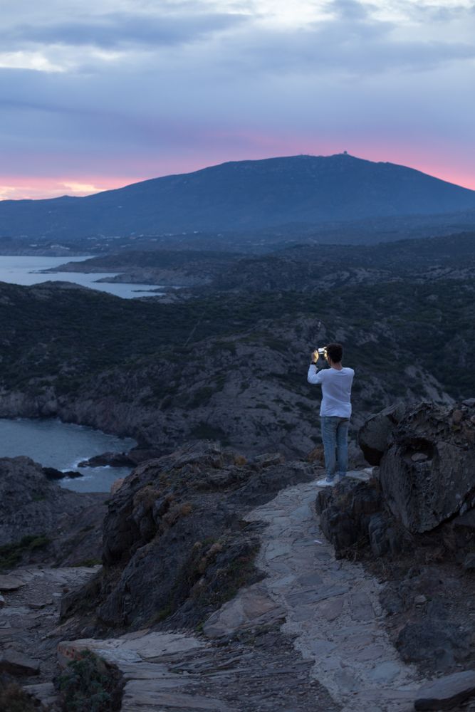 Male with smartphone overlooking the ocean at dusk, portrait