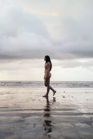 Side view of a young woman walking on the beach