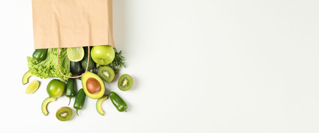Paper bag with vegetables and fruits on blank background