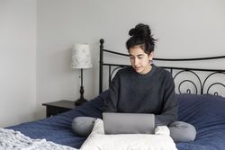 Young female working from her bed