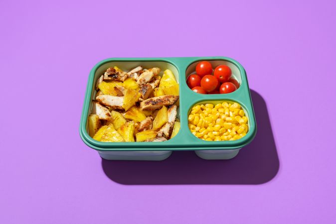 Summer salad in a lunch box isolated on a purple background