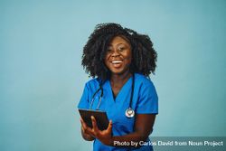 Portrait of laughing Black medical professional dressed in scrubs with tablet 49P1E5
