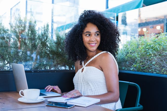 Smiling Black woman working on laptop in cafe