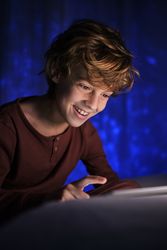 Smiling boy using tablet in dark room