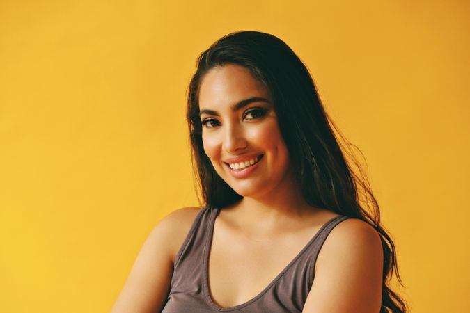 Smiling Hispanic woman looking at camera in yellow room, copy space