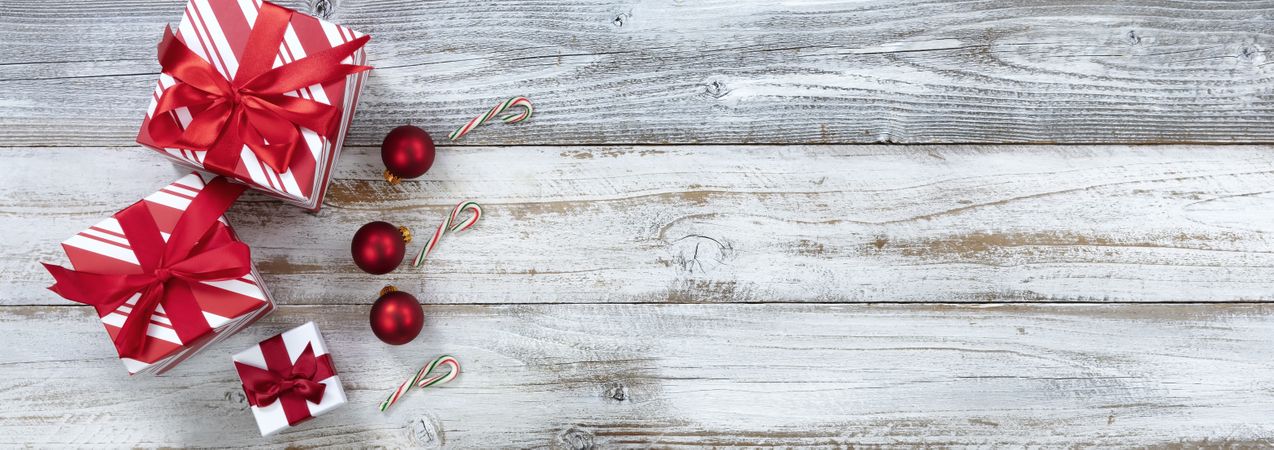 Merry Christmas with boxed gifts and ball ornaments on weathered wooden background for the season
