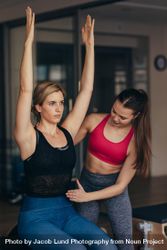 Female pilates trainer helping woman during training 4OxQob