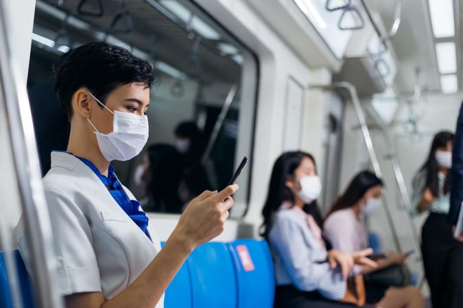 Side view of woman in facemask sitting in metro train