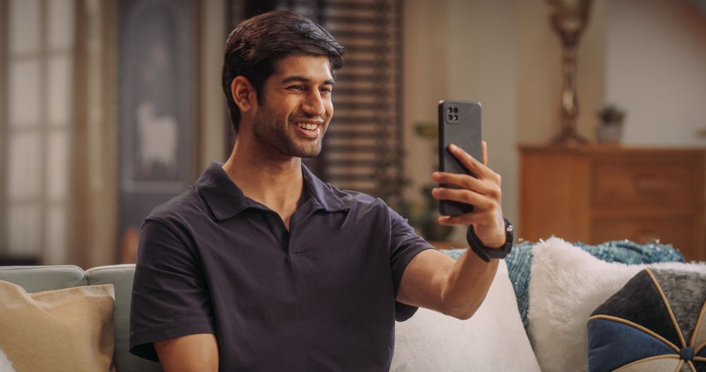 Indian Man Using Smartphone while on Video Call at Home, Doing Remote Work