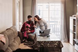 Young couple expecting baby having fun with dog at home
