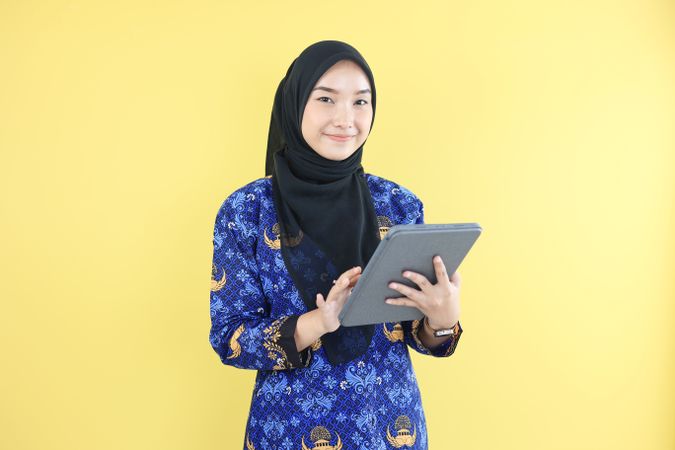 Young Worker Wearing Korpri Batik Uniform Holding Tab.