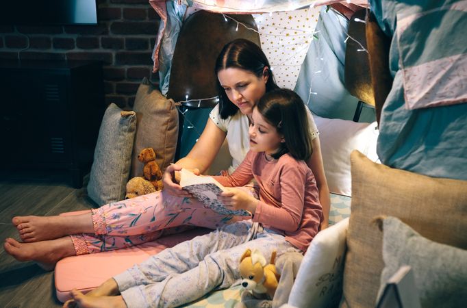 Mother and daughter reading a book in a diy tent