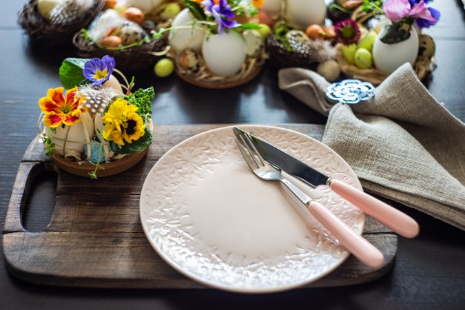 Easter holiday table setting with pink plate surrounded by decorative eggs and colorful flowers