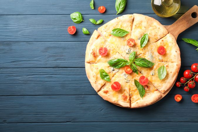 Cheese pizza, tomatoes and olive oil on wooden background, copy space