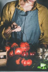 Woman in yellow holding wire basket full of tomatoes