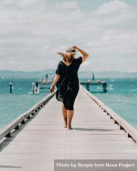 Woman walking on dock on beach 0vrLR0