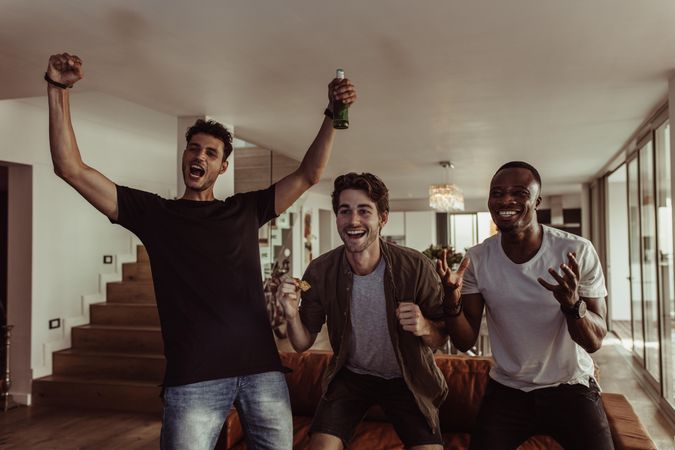 Three friends jumping in excitement while watching television