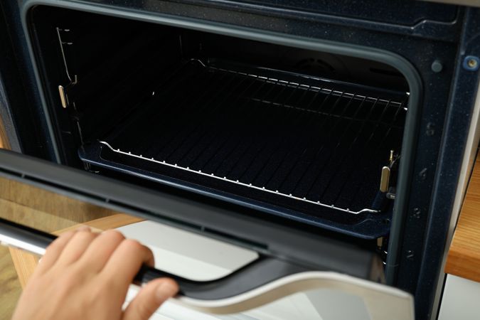 Young woman hand open empty modern oven