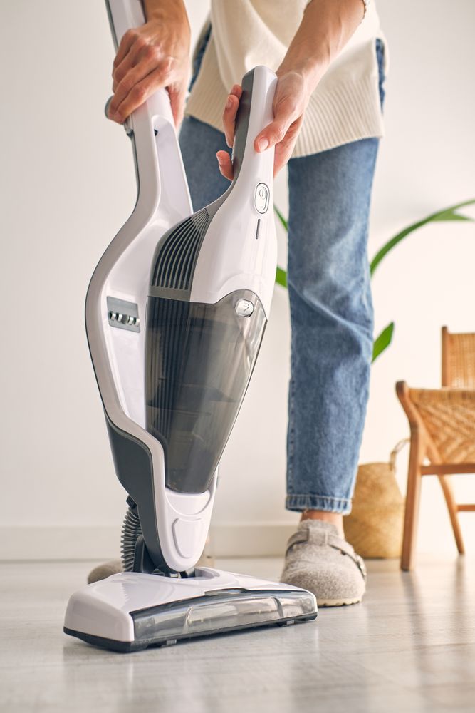 Anonymous woman removing container from modern upright vacuum cleaner