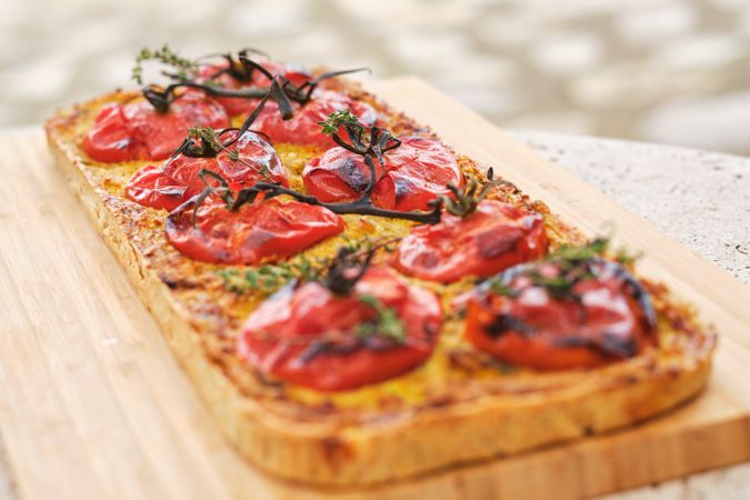 Tasty vegetarian pizza with tomatoes on cutting board