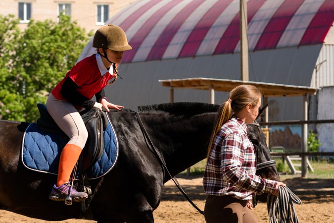 Young rider communicates with instructor during horseback session.