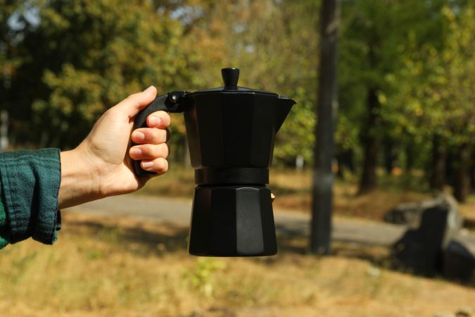 Female hand in shirt hold coffee maker outdoor