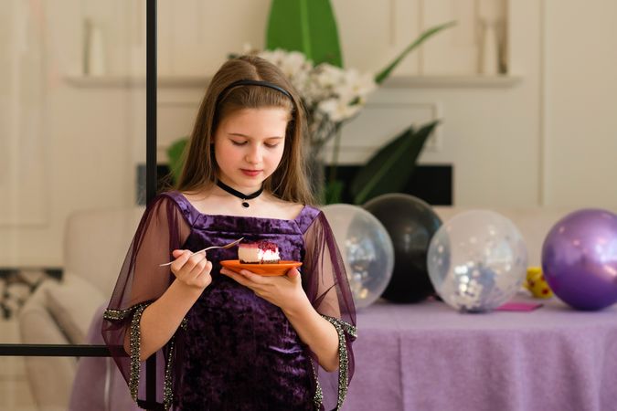Girl enjoying a piece of cake at birthday party.