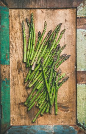 Scattered pieces of  asparagus, on wooden board, vertical composition