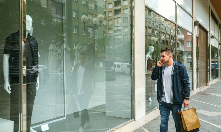 Man with shopping bags in front clothing store