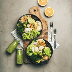 Two vegetarian bowls, with smoothie, on placemat, bread board, vertical composition