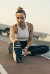 Fit woman doing a hamstring stretch on a running track after her workout