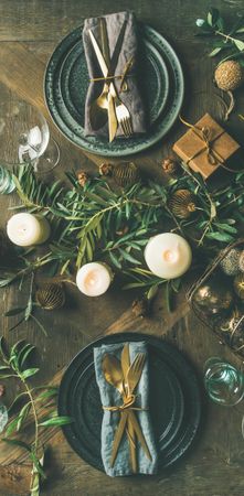 Festival holiday table setting on wooden table, with gold ornaments and branches, narrow composition