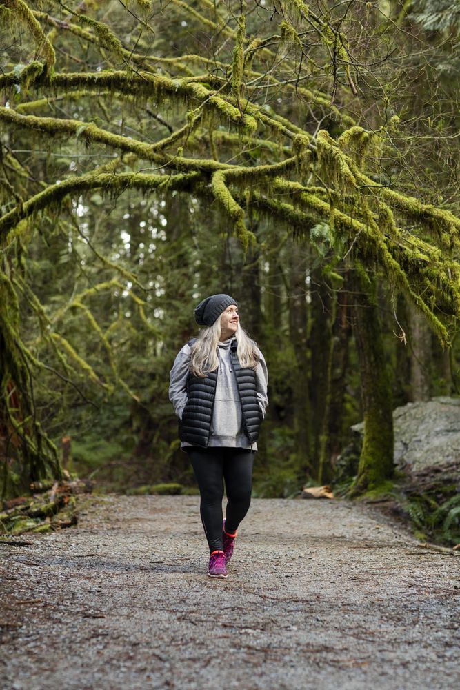 Older woman happily walking on a forest trail