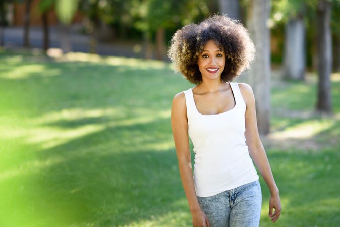 Happy Black woman with afro hairstyle walking through park