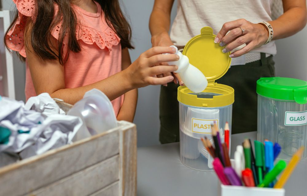Girl recycling plastic with her teacher in an ecology classroom