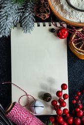 Notebook on kitchen table surrounded by baking ingredients and holiday decorations
