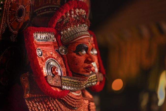 Side view of man wearing Theyyam costume as form of dance worship