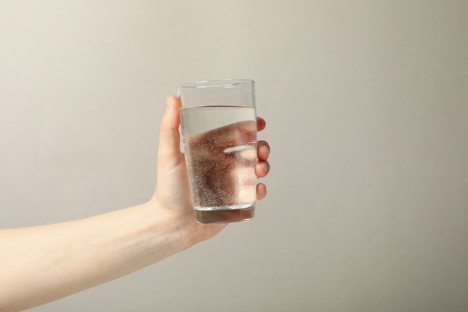 Hand holding glass of water in beige room