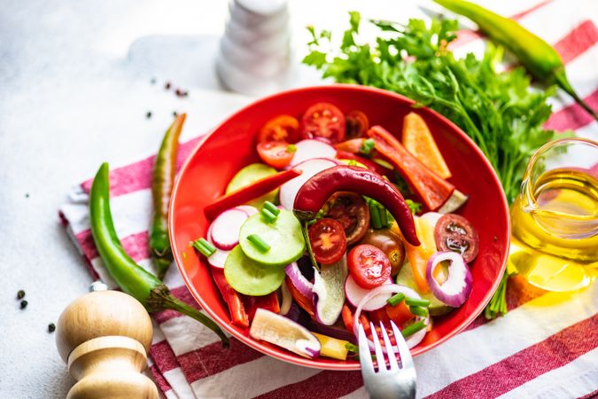 Colorful healthy raw vegetable salad served in red bowl on red napkin