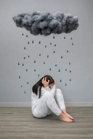 Woman under a dark storm cloud and raindrops