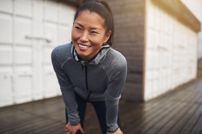 Happy woman with hands on knees after a run