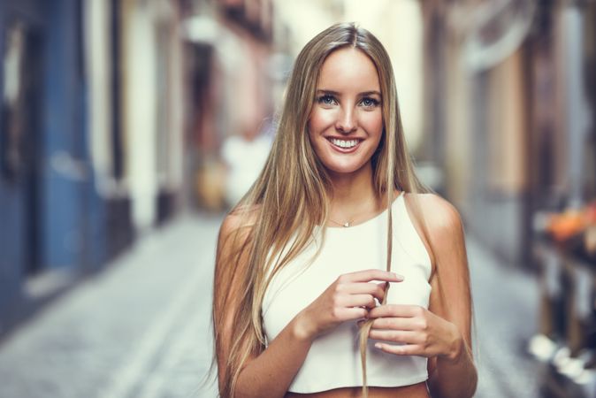 Happy chic woman playing with hair in the street