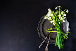 Top view of table setting for spring dinner with flowers on grey plate with copy space