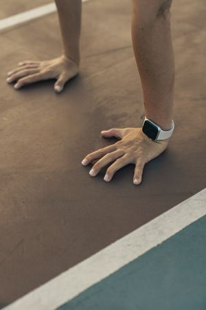 Close up of a woman's hands in a press-up position, tracking her workout with a smartwatch